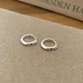 Detailed close-up view of elegant silver hoop earrings with a blue zircon stone inlay - Blue Zircon Style / Silver
