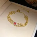 Detailed view of a vintage hollow gold bracelet featuring an oval red zircon center stone - Gold Magenta