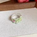 Gros plan d'une bague florale en émail vert avec perle sur fond de tissu - Style Pétale à Texture 3D (HR3114)