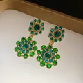 Close-up of vintage-style hollow earrings with vibrant green and blue crystal accents - Earrings / Green