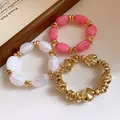 Vista detallada de tres pulseras elásticas de estilo vintage con cuentas de acrílico y oro. - Set de tres piezas / Rosa