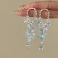 Detailed macro view showing the light blue stone tassels on silver rhinestone hoop earrings - Floral Tassel Style (HE34191) / Blue