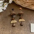 Close-up of handmade forest-style earrings featuring wooden beads and botanical seeds - Vintage Plant Fruit Style / Gold with Coffee