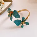 Detailansicht eines Vintage-Armreifs mit blaugrüner Emaille-Blume und Goldakzenten. - Blau