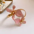 Eleganter goldener Metall-Armreif mit detaillierten rosa Emaille-Blumenornamenten. - Rosa