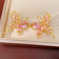 Detail view of gold plated butterfly stud earrings with sparkling pink cubic zirconia stones. - Stud Earrings (Silver Pin) / Pink