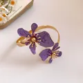 Nahaufnahme einer lila emaillierten Blumen-Armspange mit goldener Metalloberfläche - Lila