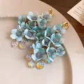 Detailed macro view of blue fabric flower tassel earrings with iridescent heart charms - Silver Post Flower Tassel Earrings / Blue