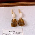 Detailaufnahme französischer Vintage-Resin-Ohrringe mit olivgrünen Anhängern. - Weiß-Kaffee