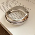 Primo piano di un ampio bracciale rigido irregolare color argento con finitura lucida - Stile 2