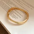 Vista ravvicinata di un bracciale rigido dorato lucido irregolare su un libro d'epoca - Stile 7