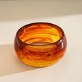 Macro view of a thick amber acrylic bangle with elegant tortoiseshell marbled texture - Amber Brown