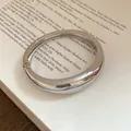 Dettaglio di un bracciale rigido argento liscio e irregolare con finitura lucida - Stile 6