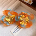 Macro detail of Bohemian style orange and blue chiffon flower earrings with silver needles. - Blue/Yellow/Orange