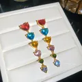 Gros plan exquis de zircons multicolores en forme de cœur sur boucles d'oreilles dorées - Style Coeur / Coloré
