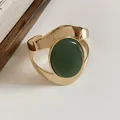 Close-up of a gold wrinkled metal cuff bracelet with a large green oval stone - Green Gemstone Pleated Style / Gold
