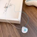 Detailed view of shell pendant necklace with blue gemstone and bicolored cord - Round Style with Shell / Blue