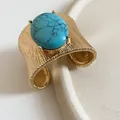 Detailed view of textured gold cuff bracelet with large oval turquoise stone. - Blue Gemstone Pleated Style / Gold