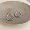 Dettaglio di orecchini a cerchio in argento testurizzato in una ciotola di ceramica. - Fibbia per orecchini a trama tonda (HE32047) / Argento
