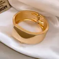 Detailed view of a wide gold-tone metal bangle featuring a polished rectangular plate design - Widened Panel Hinge Style / Gold