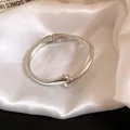 Close-up of minimalist silver-toned metal bangle bracelet on elegant soft satin fabric - Minimalist Arc Clasp Style / Silver