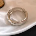 Detailed view of a polished silver-colored chunky metal bangle resting on white silk - Wide Rounded Cuff Style / Silver
