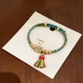 Detailansicht eines handgewebten fünf-Farben-Armbands mit Friedensanhänger und bunter Quaste - Frieden und Freude