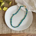 Dettaglio di una collana di fiori di perline blu e verdi fatta a mano su un piatto - Collana Blu Verde