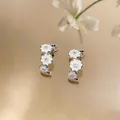 Detail view of elegant C-shaped earrings with white enamel flowers and zircon centers. - White