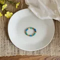 Primo piano di un anello vintage con perline di vetro blu e oro su un piatto bianco - Stile Rotondo / Anello Tondo Blu Verde