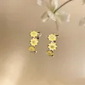 Detail view of C-shaped earrings with yellow enamel flowers and sparkling zircon center. - Yellow