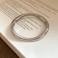 Detailed view showing the polished silver wavy metal bangle design on a paper background - Irregular Wavy Pleated Style / Silver