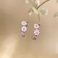 Macro detail view of C-shaped earrings with pink enamel flowers and zircon centers - Pink