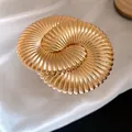 Close-up macro detail of a luxury pleated gold-colored metal flower bracelet with fine ribbing - Radial Wave Spiral Style / Gold