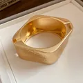 Close-up detail of a golden metal bracelet featuring a textured wrinkled hammered finish - Rounded Square Pleated Style / Gold