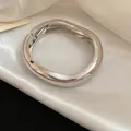 Detail macro view of polished silver metal wavy wrinkled bracelet on white satin fabric - Folding Buckle Wavy Style / Silver