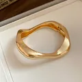 Close-up of gold metal crumpled bangle with unique wavy design and hinge - Spring Cuff Wavy Style / Gold