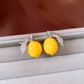 Close-up of vibrant yellow resin lemon jewelry with sparkling zircon leaves - Lemon Stud Earrings / Yellow