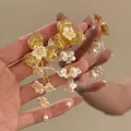 Detailed view of French retro gold flower earrings with white bell floral tassels - French Vintage Flower Tassel Drop Earrings (HE34213) / Silver Needle / Gold-White