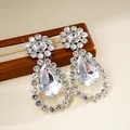 Dettaglio macro di lussuosi orecchini a goccia con strass e incastonature elaborate. - Argento