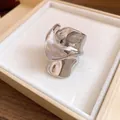 Primo piano di un anello d'argento ondulato irregolare in una scatola regalo color crema. - Argento