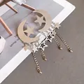 Close-up detail of silver crescent moon and star tassel earrings displayed on a magazine - Star Moon Tassel Style (HE33731) / Silver