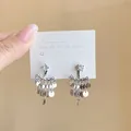 Detailed view of elegant silver sequin tassel earrings featuring a sparkling crystal stud - Silver