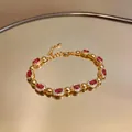 Vista dettagliata di un bracciale in oro vintage di lusso con pietre rosse ovali e cristalli - Oro-Rosa