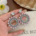 Close-up detail of vintage hoop drop earrings with pink zircons and white pearls held in hand - Vintage Large Round Loop Drop Style / Silver Base with Pink & Green Zirconia