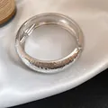 Elegant silver metal bangle with a unique pleated hammered finish on white silk - Hammered Pleated Hinge Style / Silver