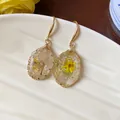 Elegant gold-toned wire-wrapped resin earrings with embedded yellow dried flowers. - Gold-Yellow