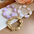 Close-up of irregular geometric acrylic elastic bracelets in gold, purple, and white. - Irregular Beaded Bracelet Set / Gold-Purple-Transparent