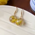 Close-up of resin sphere earrings with yellow dried flowers and gold hooks - Gold-Yellow