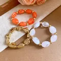 Close-up of irregular acrylic and golden metallic stretch bracelets in warm tones - Irregular Beaded Bracelet Set / Gold-Orange-Transparent